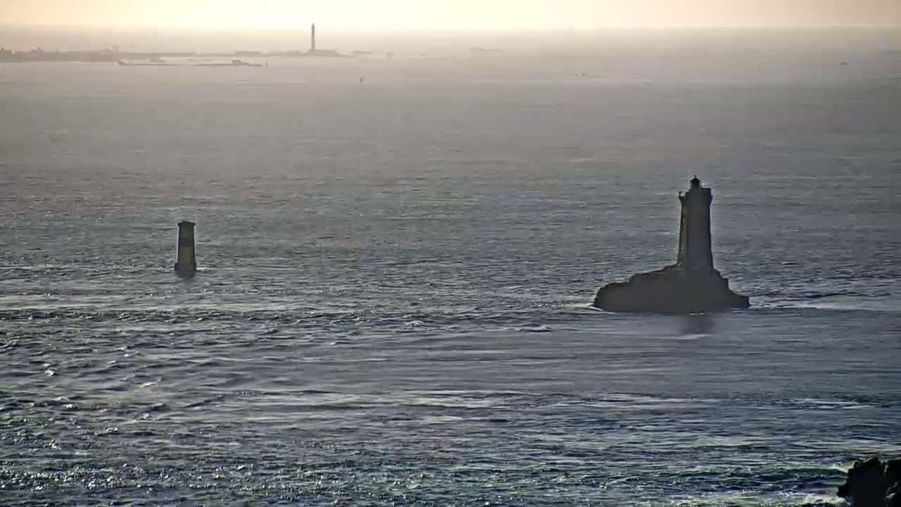 Two lighthouses stand on small islands in a hazy, gray ocean.