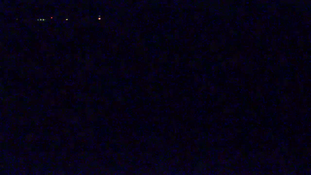 A dark, nighttime scene shows a few faint, distant lights.