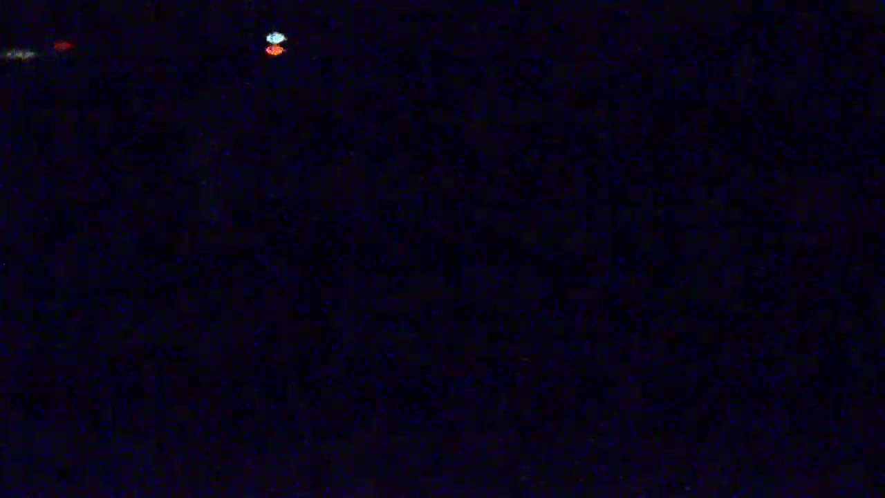 A dark, possibly nighttime scene shows a few blurry, multicolored lights in the distance.