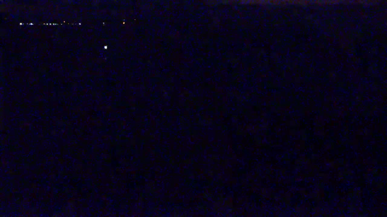 A dark, nighttime scene shows a few faint lights in the distance.