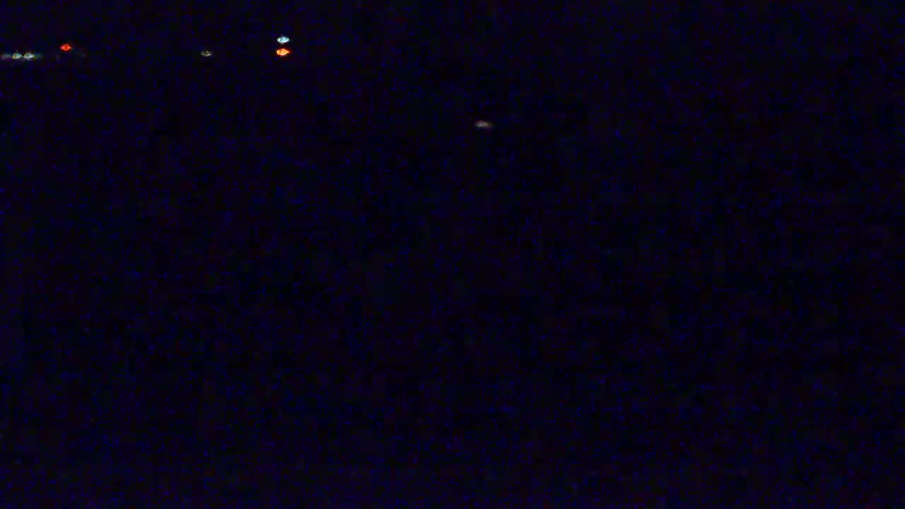 A dark, nighttime scene shows a few small, distant lights.