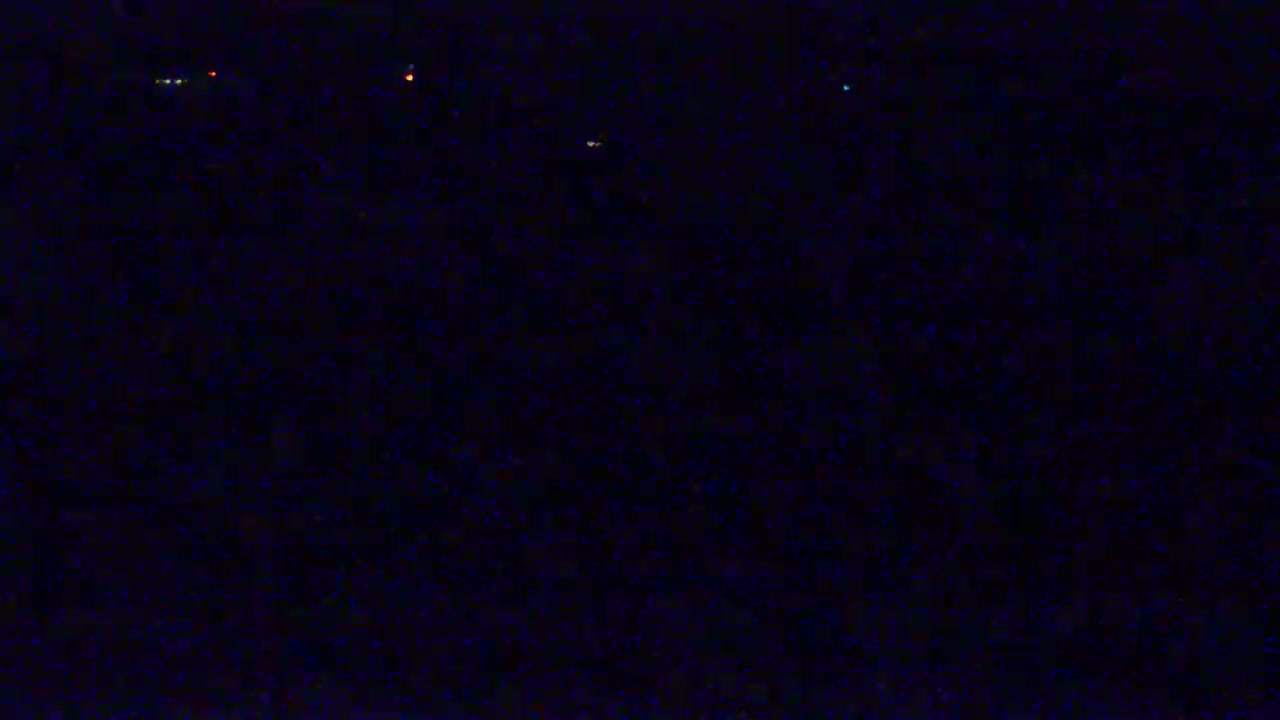 A dark, nighttime scene shows several distant, small lights against a mostly black background.