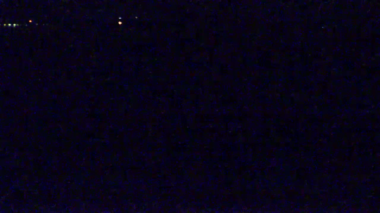 A dark, nighttime scene shows a few distant lights in the far background.