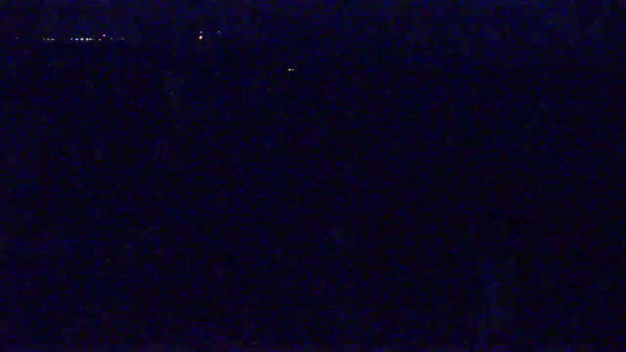 A dark, nighttime scene shows a distant line of lights on the horizon.