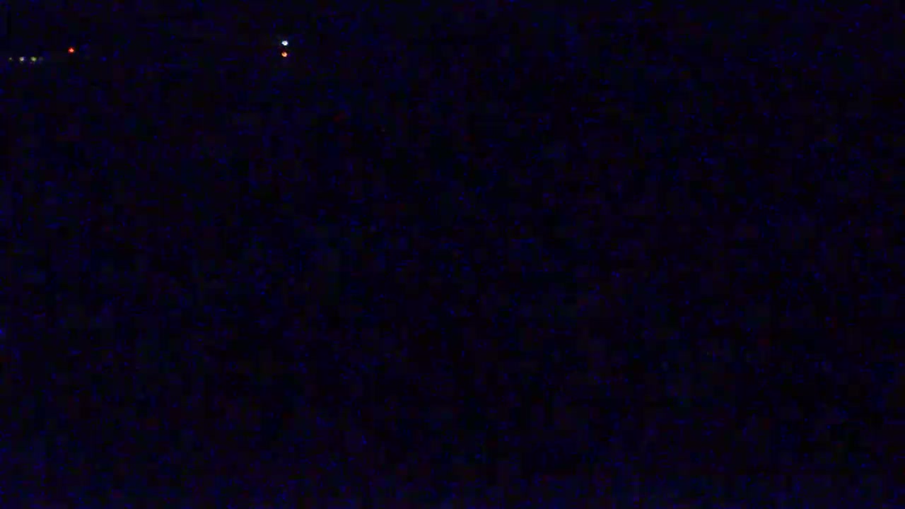 A dark, nighttime scene shows a few faint, distant lights.