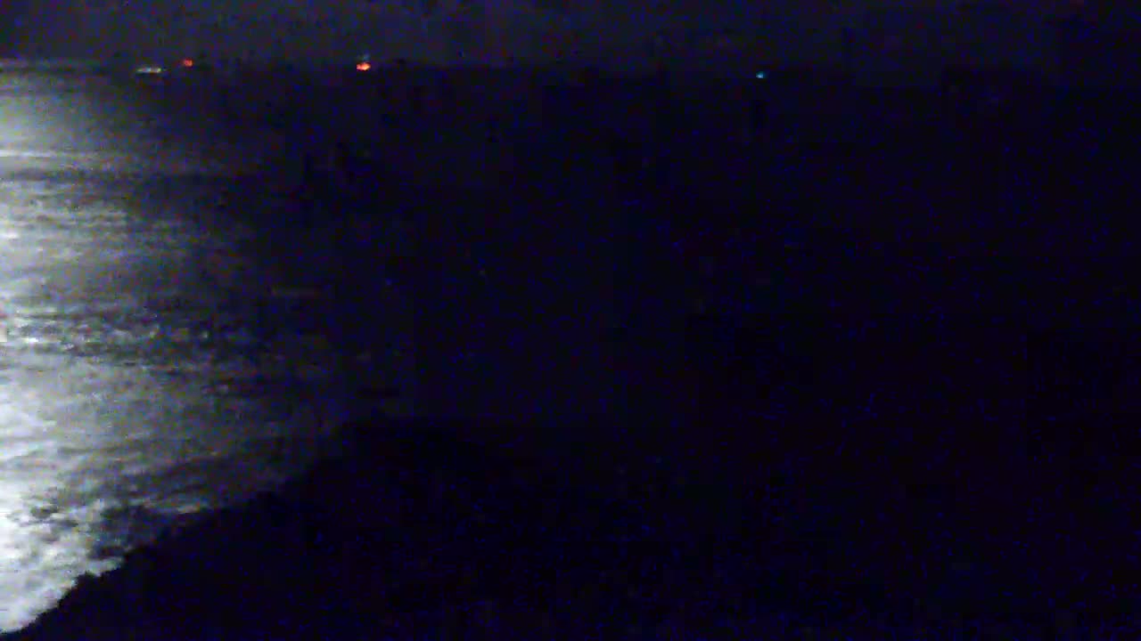 Moonlight illuminates a dark, wavy ocean at night.