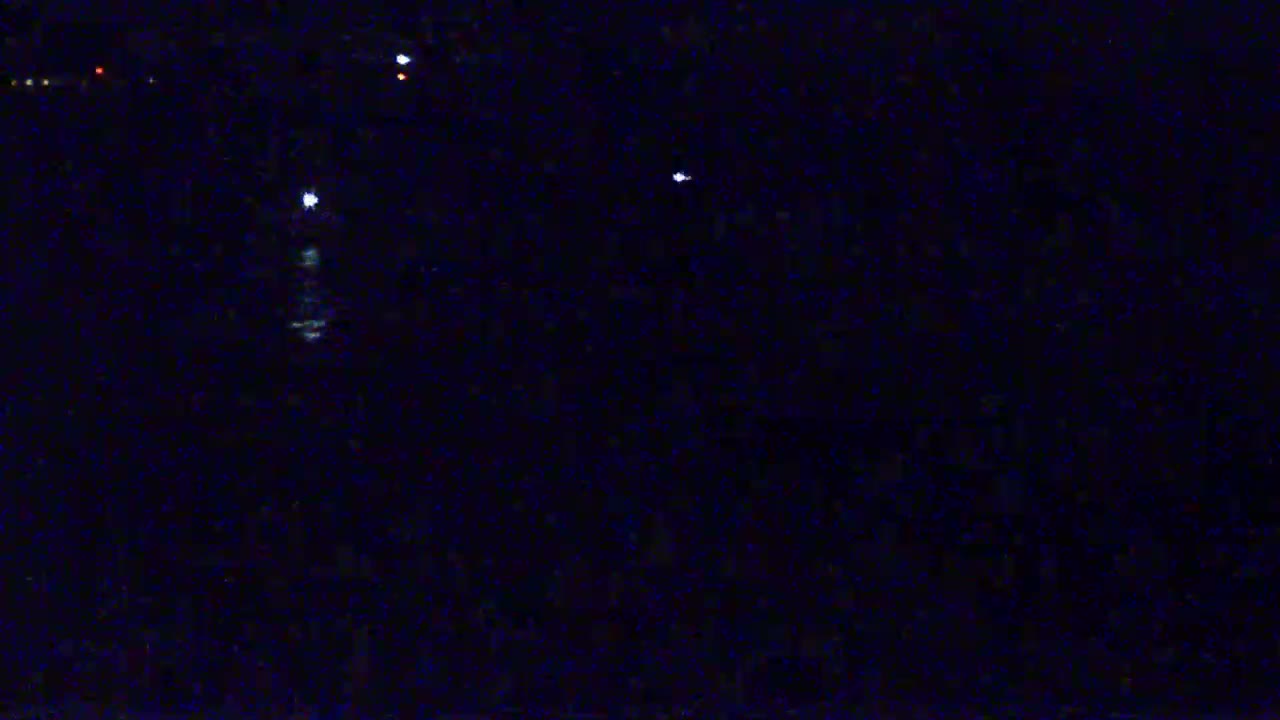 A dark, nighttime scene shows several small, distant lights against a mostly black background.