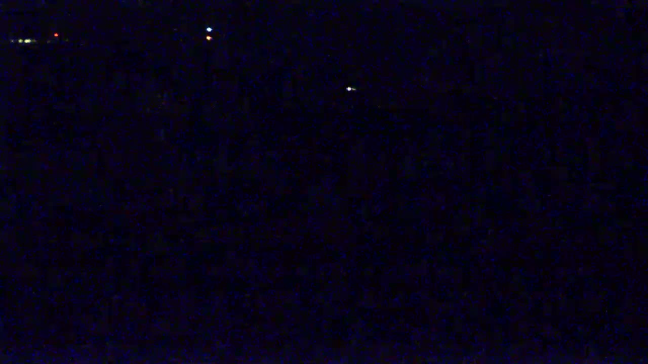 A dark, nighttime scene shows a few distant, small lights against a very dark background.
