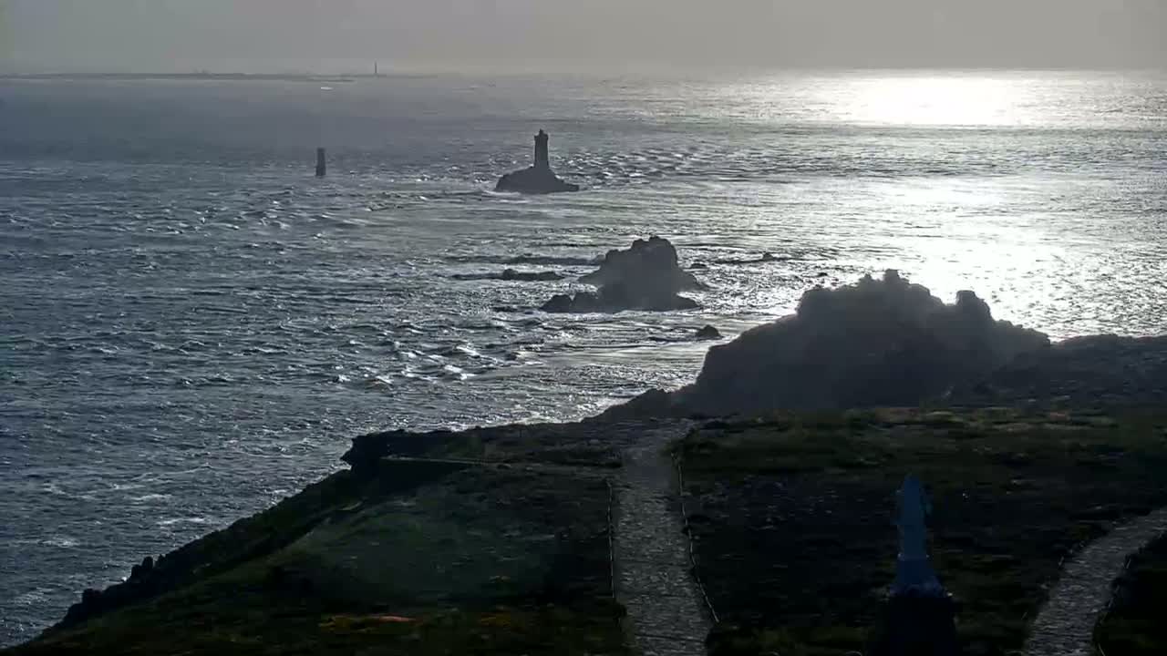 A rocky coastline with several small lighthouses visible in the distance, under a somewhat overcast sky with a calm to moderately choppy sea.