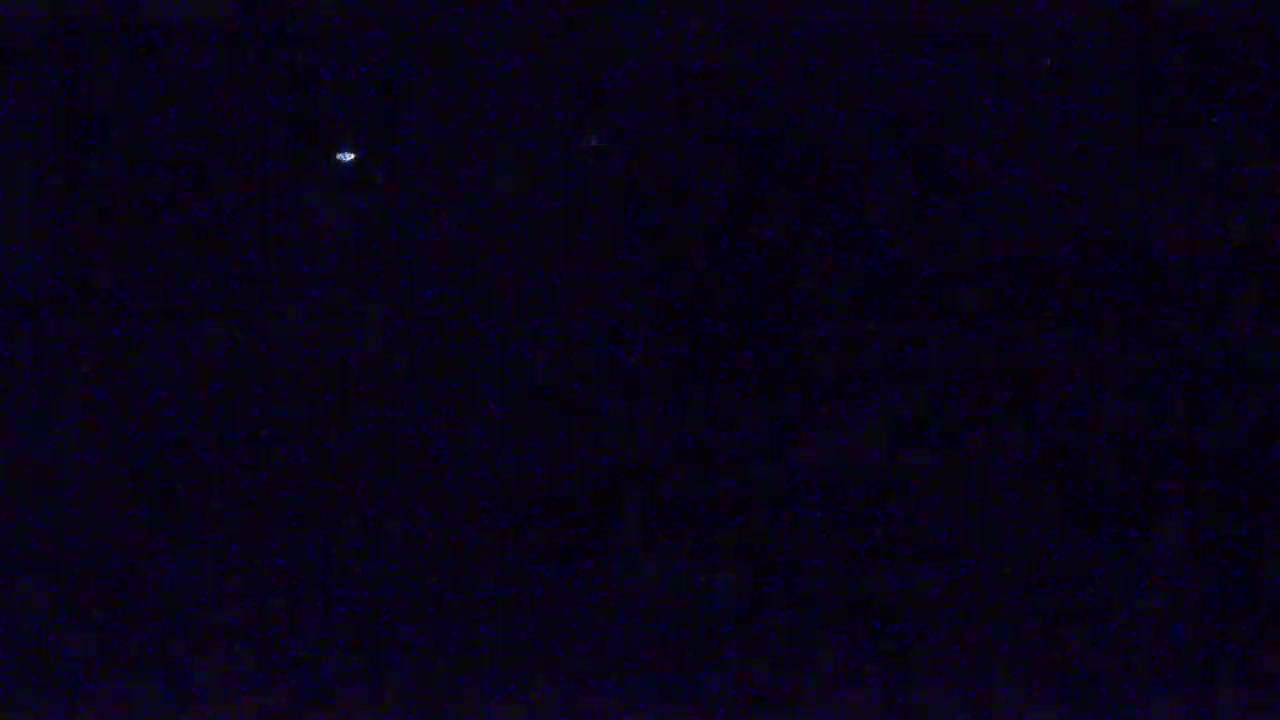 A dark, night sky shows a small, bright object and many fainter, distant lights.