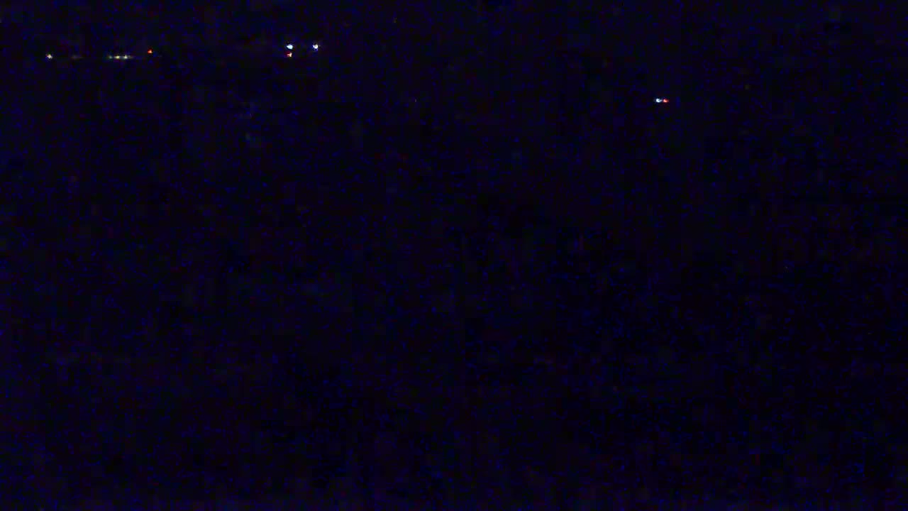 A dark, nighttime scene shows a few distant lights.