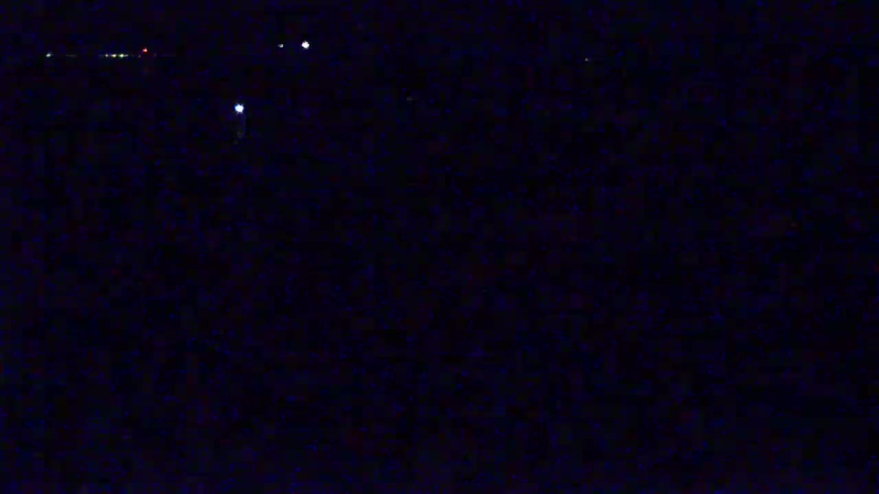 A dark, nighttime scene shows a few distant lights in the blackness.