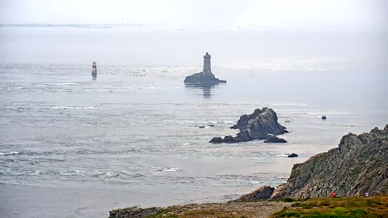 A rocky coastline with two lighthouses and a hazy ocean in the distance.