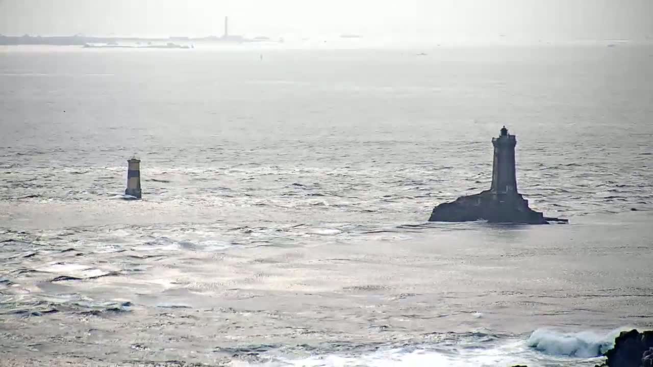 Two lighthouses stand in a choppy sea under an overcast sky.