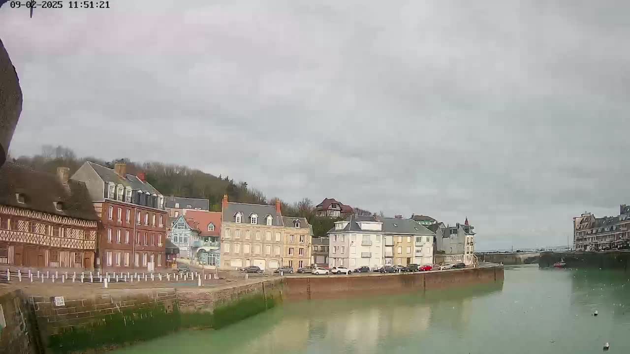 A row of buildings lines a calm waterway under an overcast sky.
