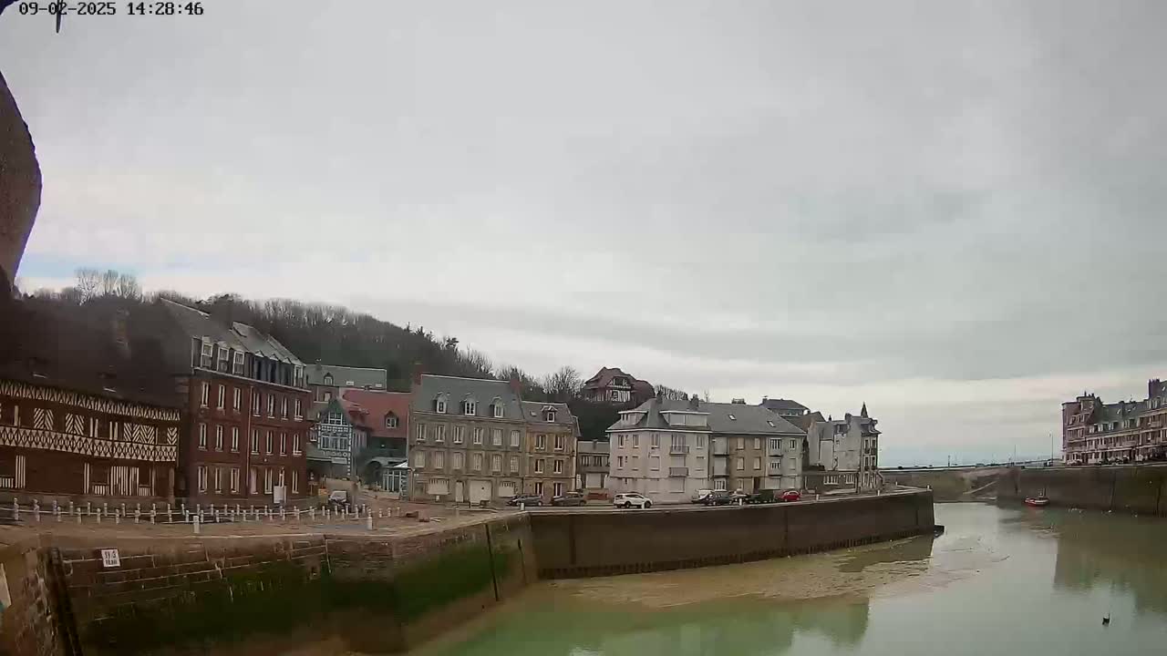 A calm waterway flows between rows of buildings under an overcast sky.
