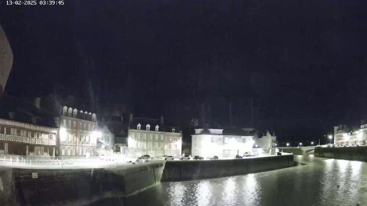 A nighttime view of a canal lined with buildings under a clear, dark sky.