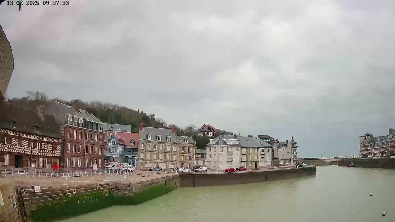 A calm waterway flows between rows of buildings on a cloudy day.