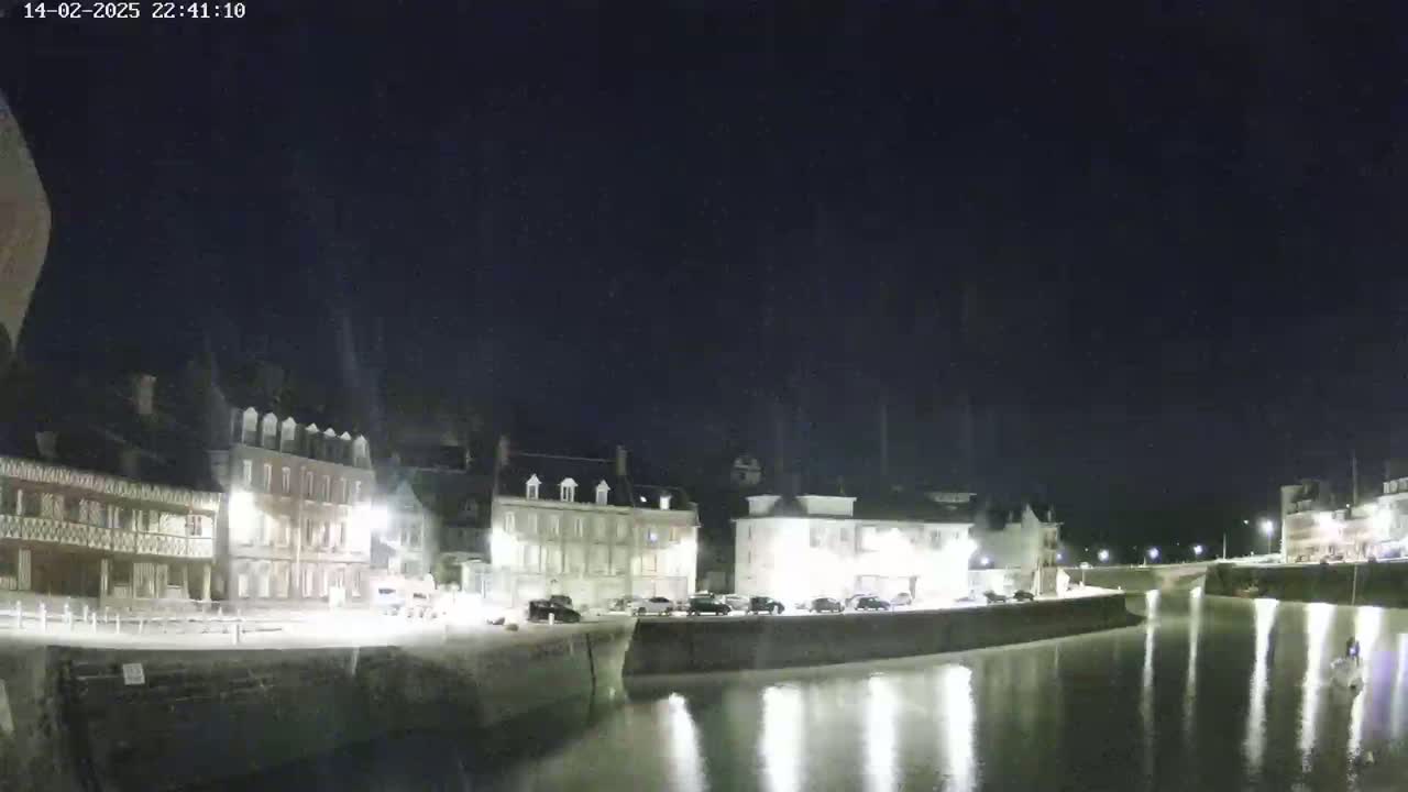 A nighttime view of a calm waterway reflecting lights from buildings along its banks.
