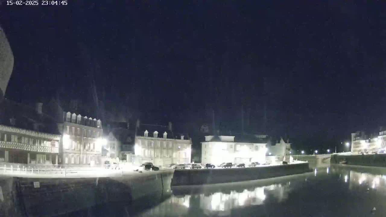 A nighttime view of a calm canal reflecting lights from buildings lining its banks.