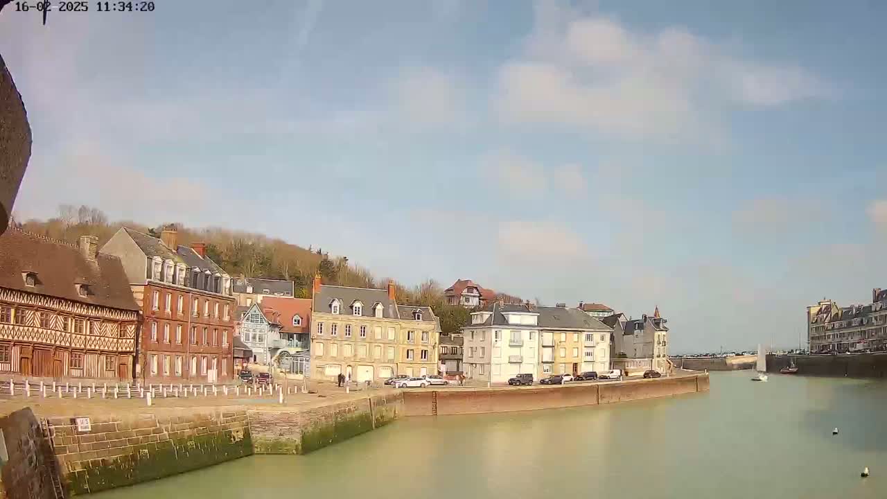 A calm waterway separates rows of historic buildings under a partly cloudy sky.