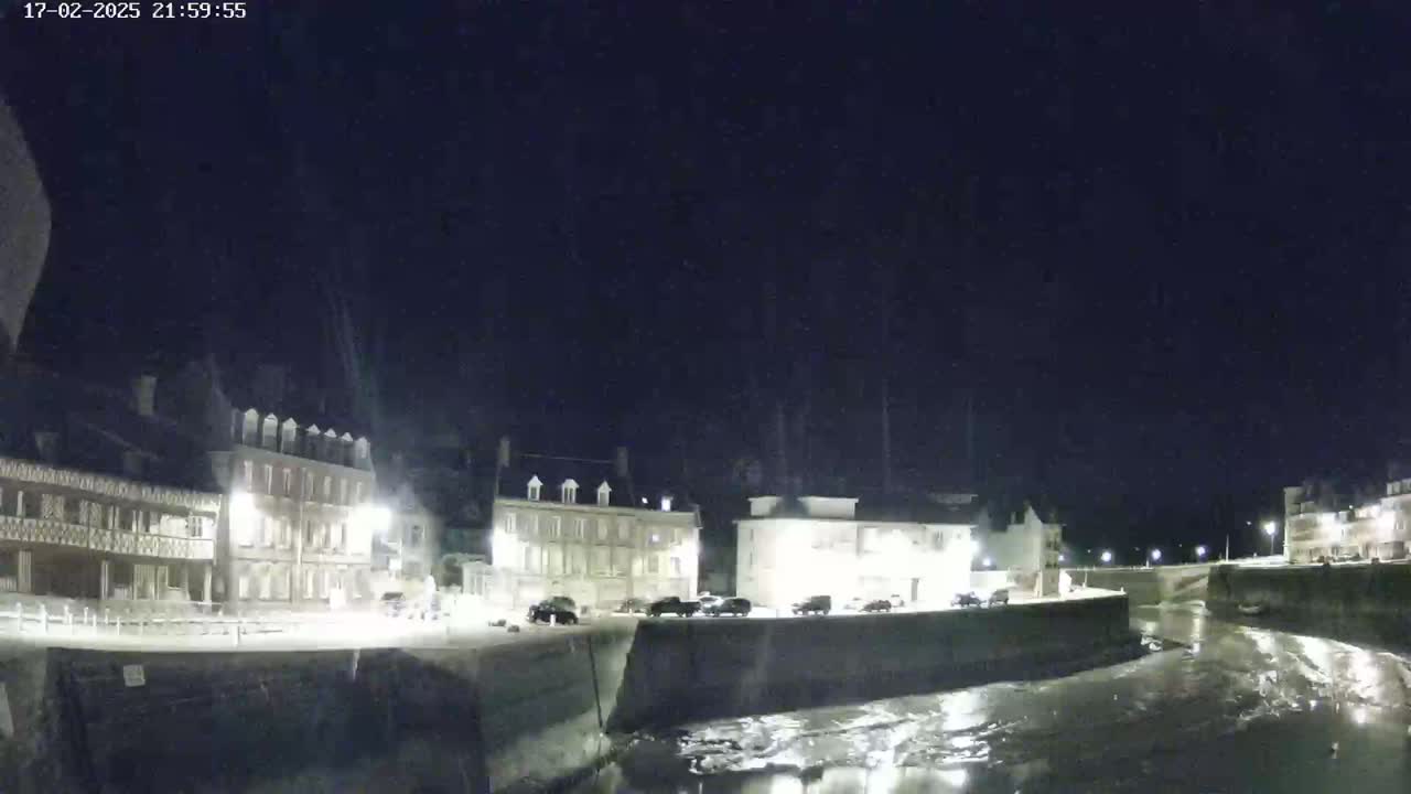 A nighttime view of several buildings along a waterway under a dark, clear sky.