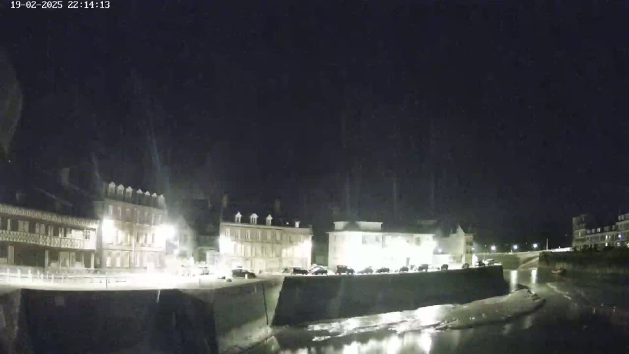 At night, several buildings line a waterfront canal under a dark, clear sky.