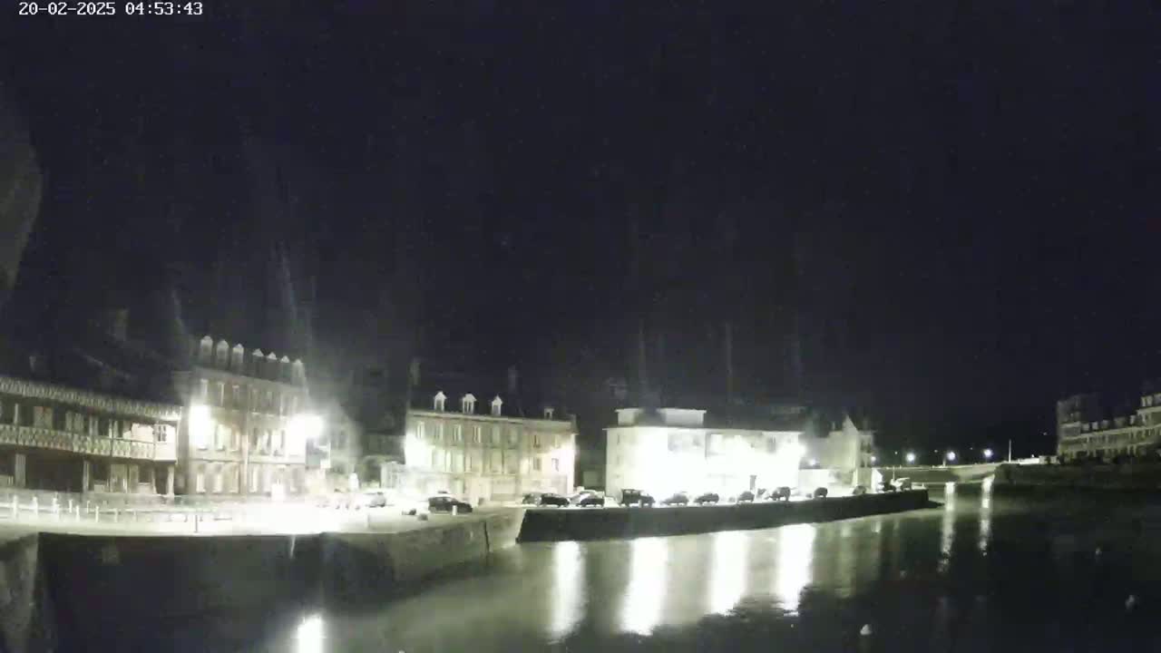 A nighttime view of a calm canal reflecting the lights of buildings along its banks.