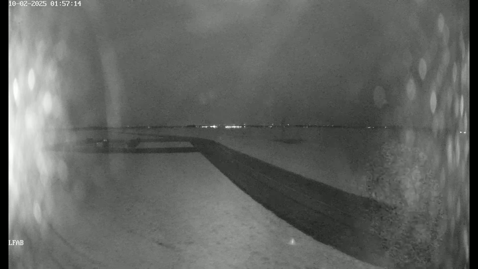 A snow-covered road stretches toward a dimly lit horizon under a dark, nighttime sky.