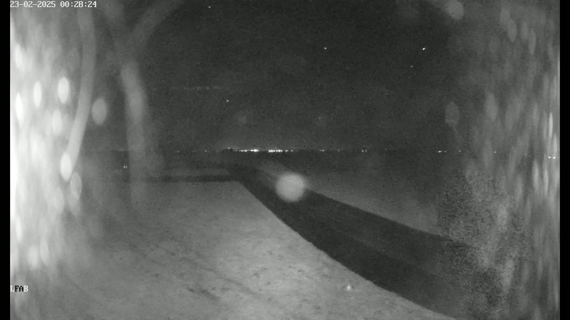 A nighttime, snow-covered landscape is visible, showing a dark road and a distant line of lights under a clear, starry sky.