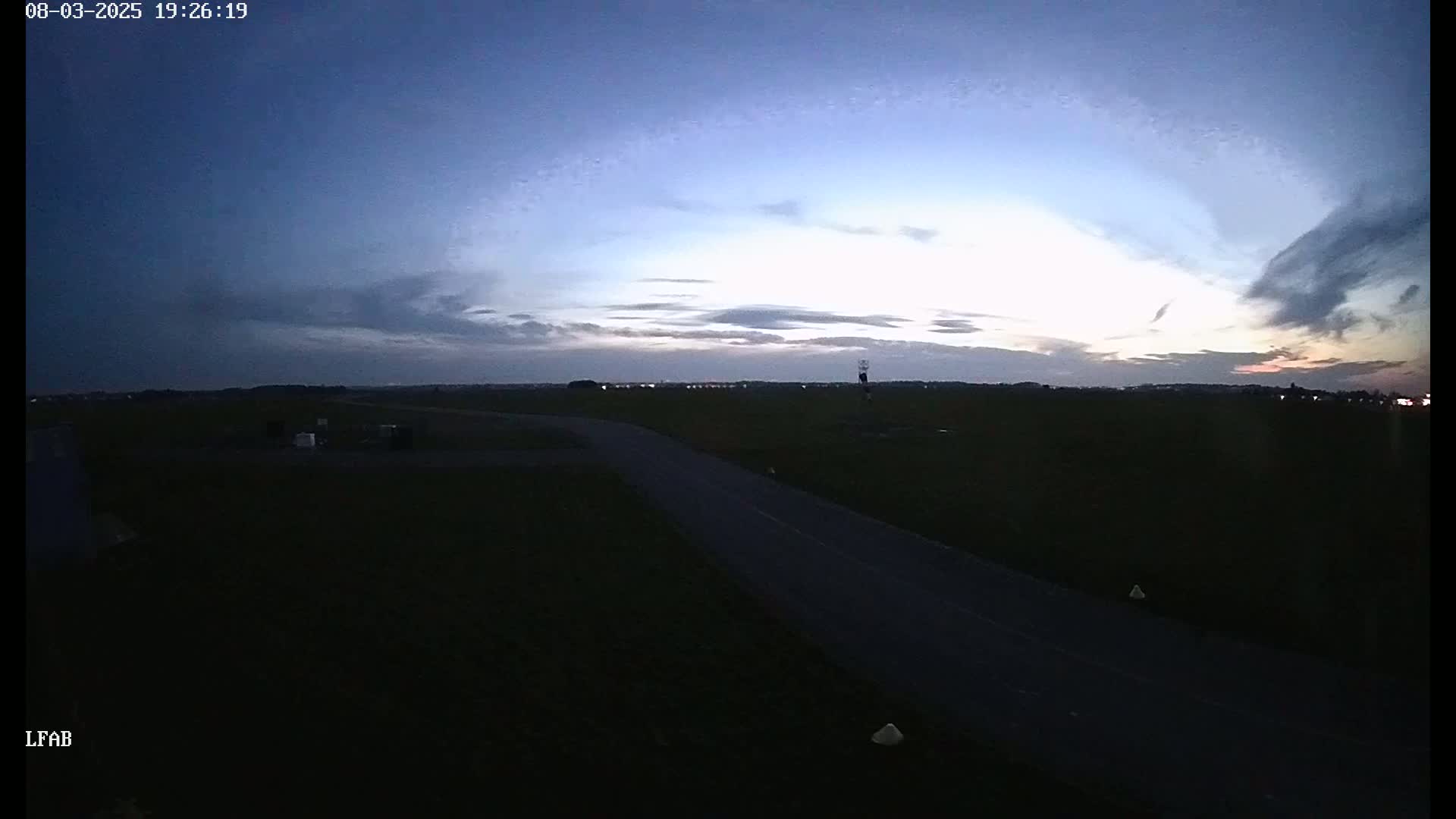 A dark road stretches into the distance under a twilight sky with thin clouds.