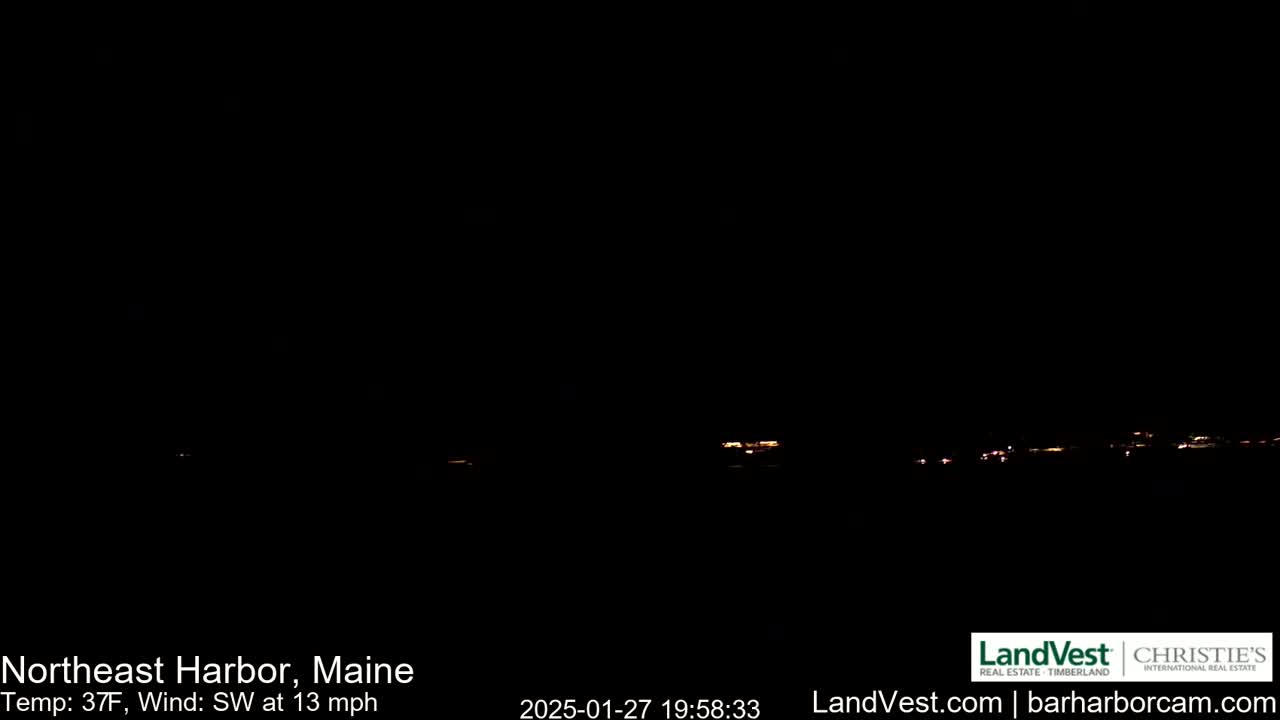 A dark nighttime scene shows a distant line of faint lights across a dark horizon under a clear, dark sky with a southwest wind at 13 mph and a temperature of 37 degrees Fahrenheit.