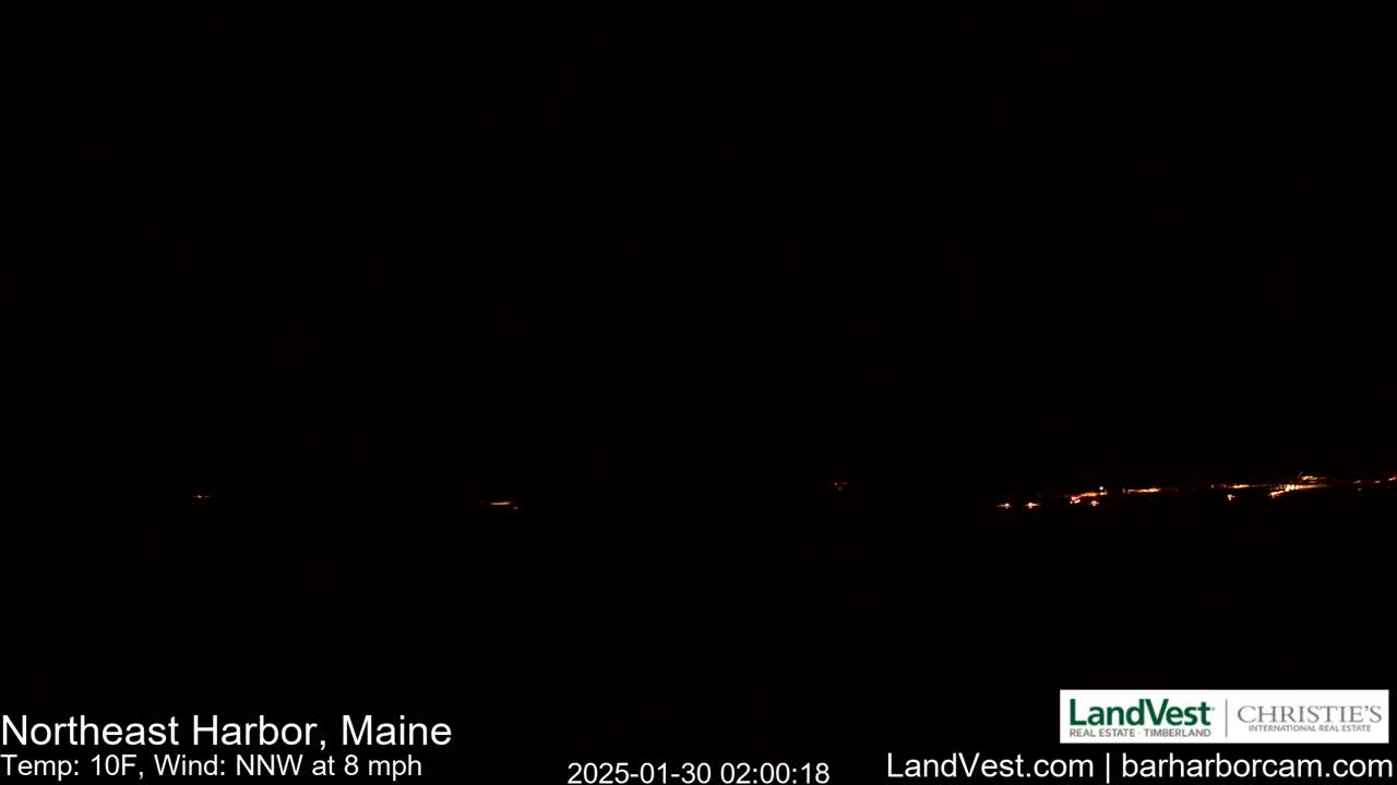 A nighttime long shot of a dark, snowless landscape with a faint line of distant lights under a clear, dark sky.