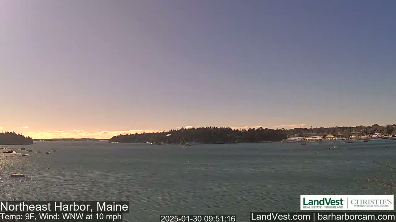 A calm harbor with a few boats, under a clear, pale-orange sky, and a light wind.