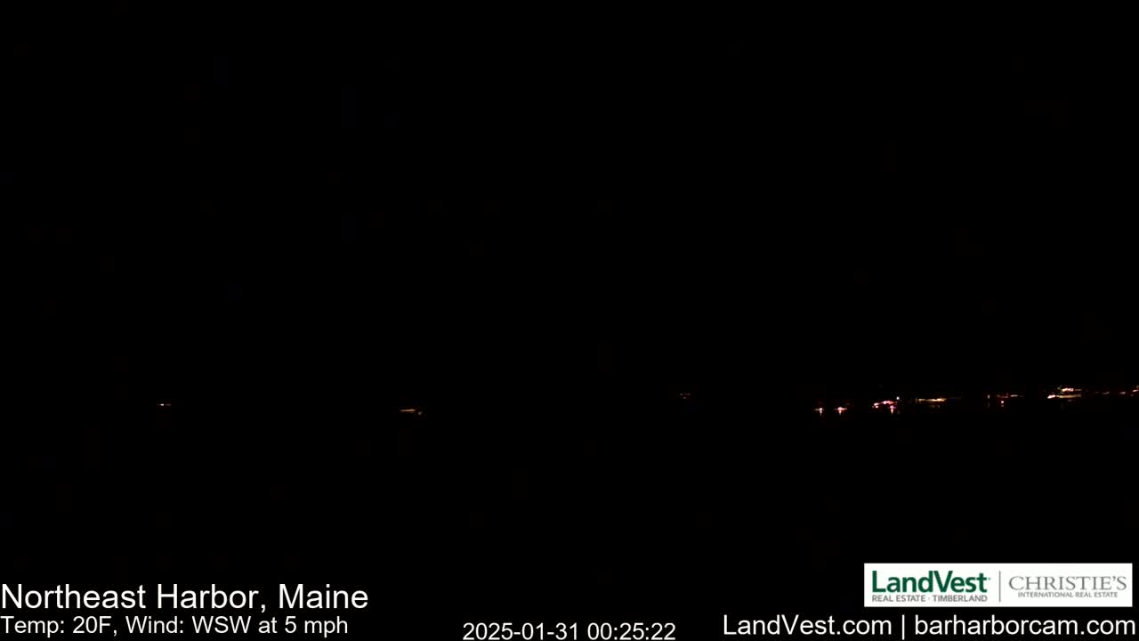 A dark nighttime scene shows a distant line of faint lights across a black horizon under a clear, dark sky, with a temperature of 20°F and a west-southwest wind at 5 mph.