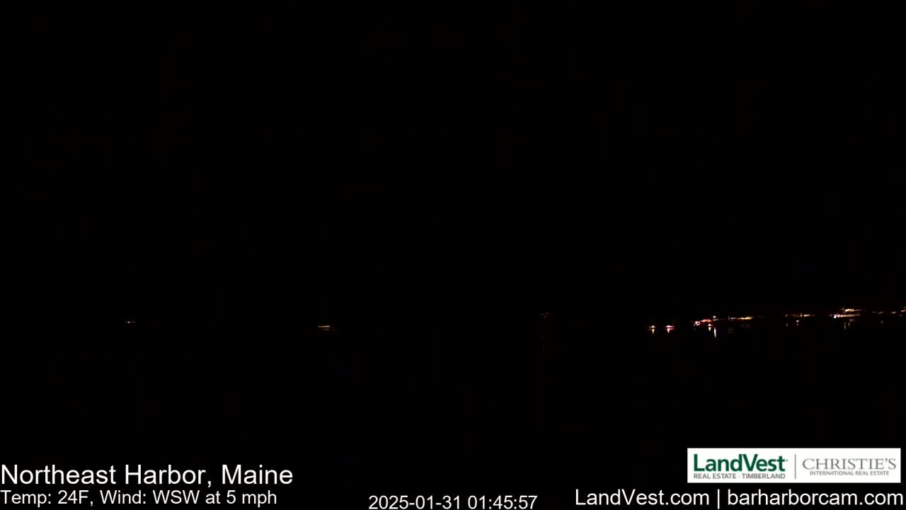 A dark nighttime scene shows a faint line of lights on the horizon under a clear, dark sky with a temperature of 24°F and a west-southwest wind at 5 mph.