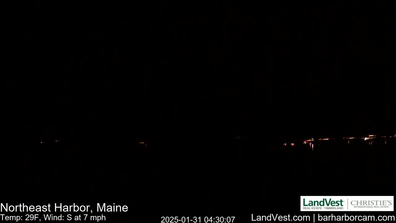 A dark nighttime scene shows a faint line of distant lights across a body of water, with a south wind blowing at 7 mph and a temperature of 29°F.
