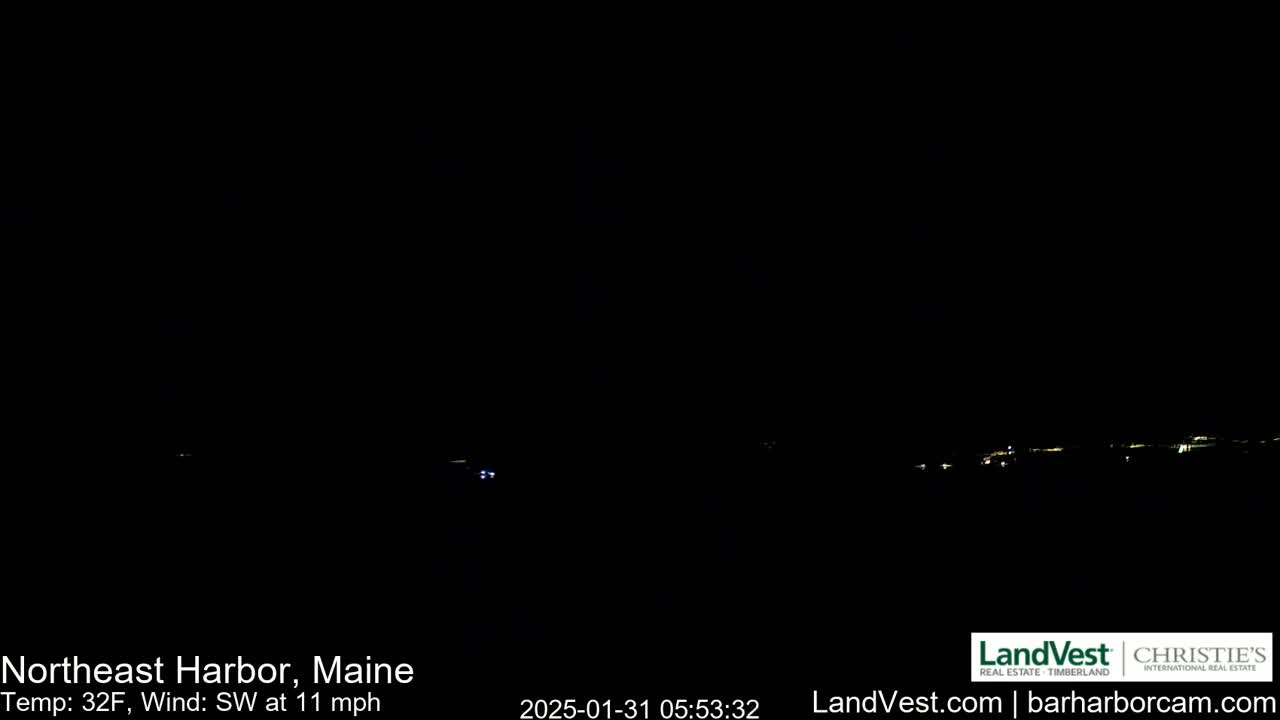 A dark, nighttime scene shows a distant line of faint lights on the horizon under a clear, dark sky with a southwest wind at 11 mph and a temperature of 32°F.