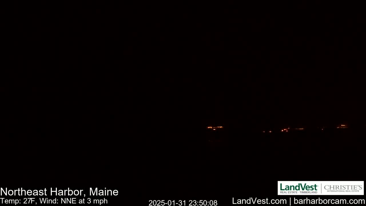 A dark nighttime scene shows a faint line of distant orange lights.