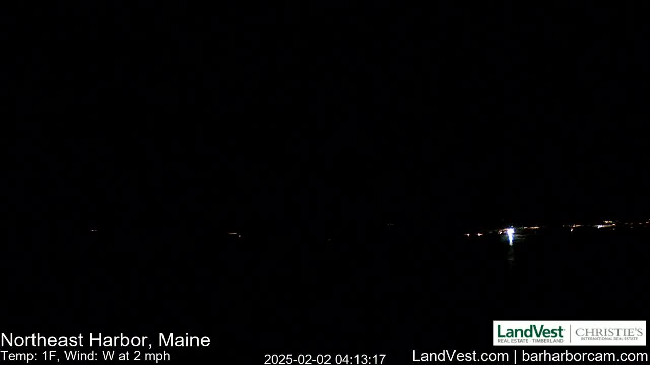 A nighttime, long shot of a dark harbor with faint lights visible in the distance, under a clear, dark sky with a temperature of 1°F and a west wind at 2 mph.