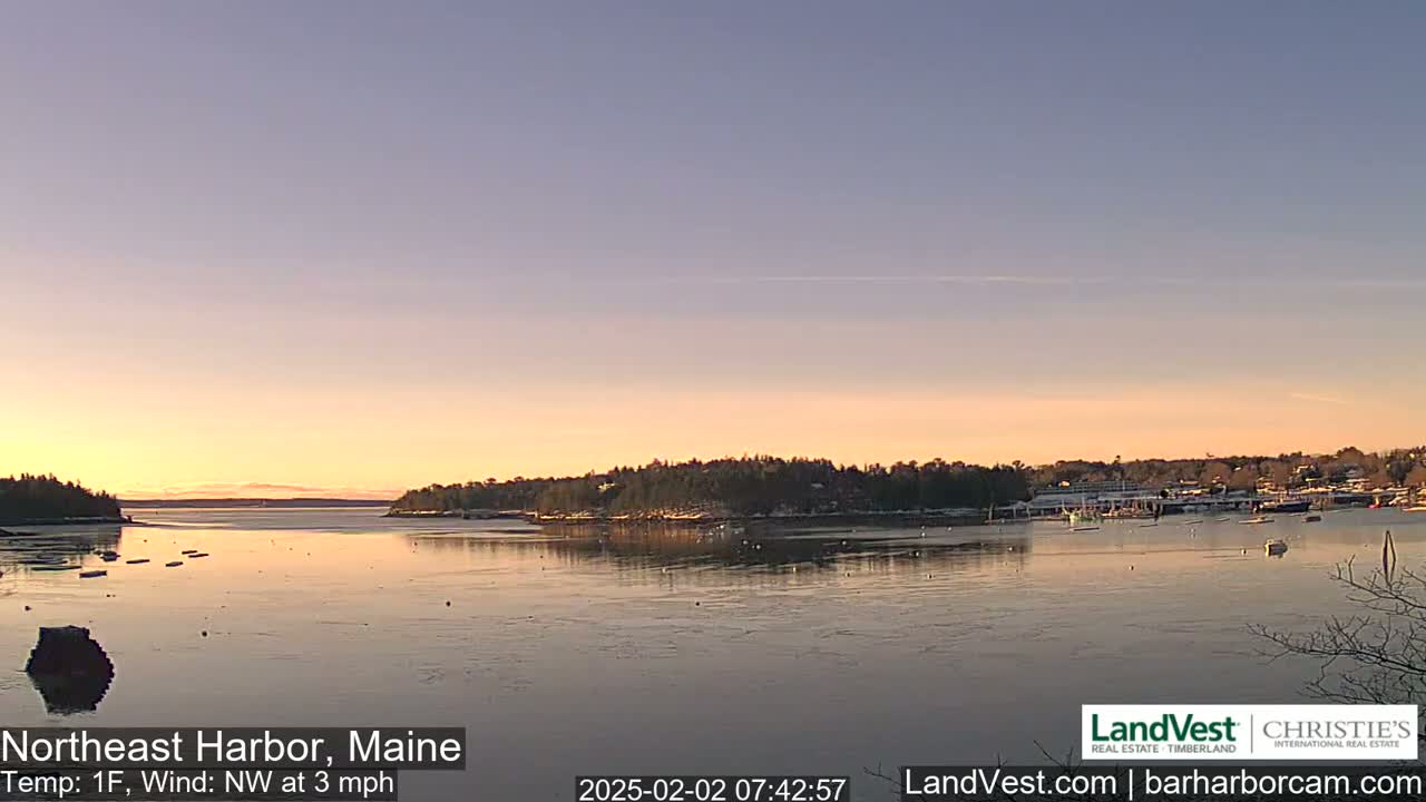 A calm harbor at sunrise, with a light northwest wind and a temperature of one degree Fahrenheit, shows partially frozen water and a few boats.