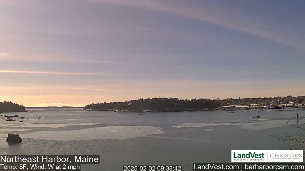A partly frozen harbor is seen at sunrise under a mostly clear sky with a light westerly wind.