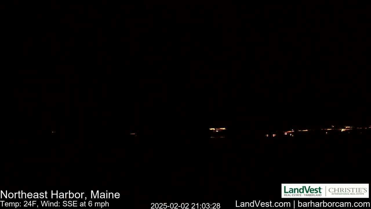 A nighttime long shot shows a dark, sparsely-lit town on the horizon under a clear, dark sky with a 24°F temperature and a 6 mph wind from the south-southeast.