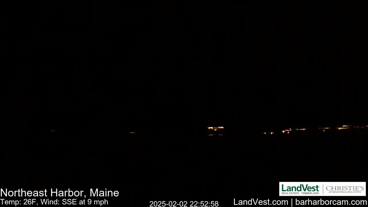 A nighttime long shot shows a faint line of distant lights across a dark horizon under a clear, dark sky with a 26°F temperature and a 9 mph wind from the south-southeast.