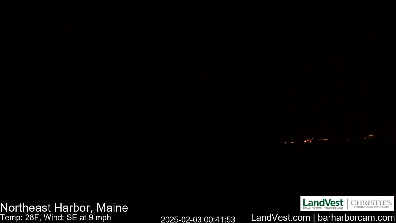 A nighttime, dark image shows a faint line of distant lights under a clear, dark sky with a southeast wind at 9 mph and a temperature of 28°F.