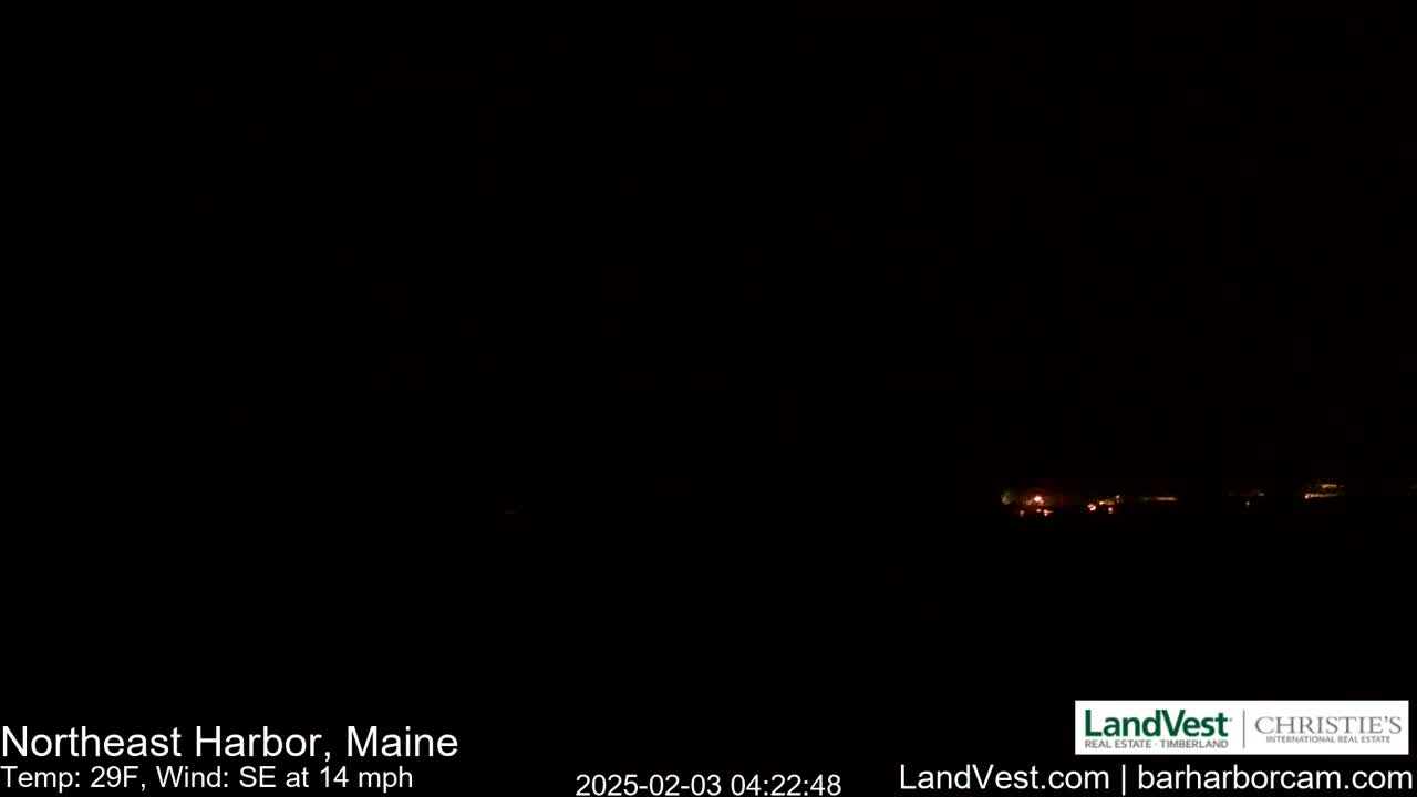 A dark nighttime scene shows a distant line of faint lights against a black sky, with a southeast wind at 14 mph and a temperature of 29°F.