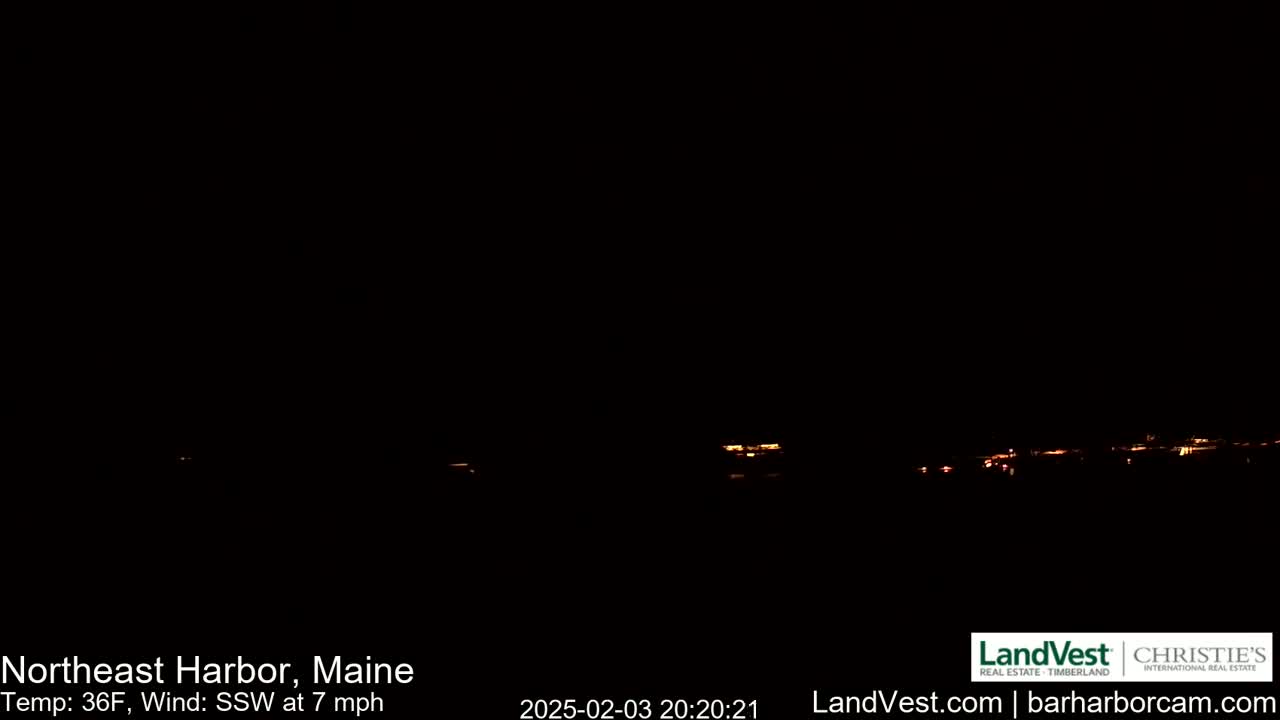 A dark nighttime scene shows a distant line of faint orange lights, under a clear, dark sky with a south-southwesterly wind at 7 mph and a temperature of 36°F.