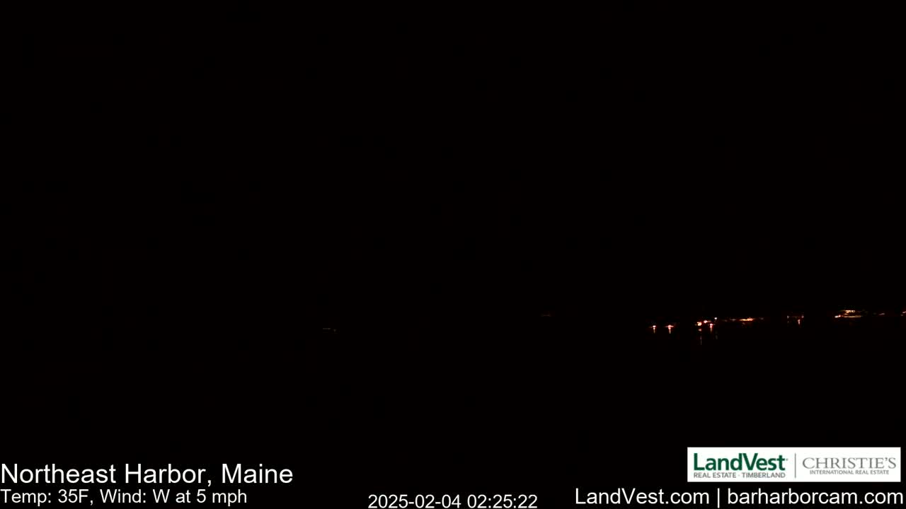 A dark, nighttime scene shows a faint line of distant lights across a body of water, with a 35°F temperature and a 5 mph west wind.