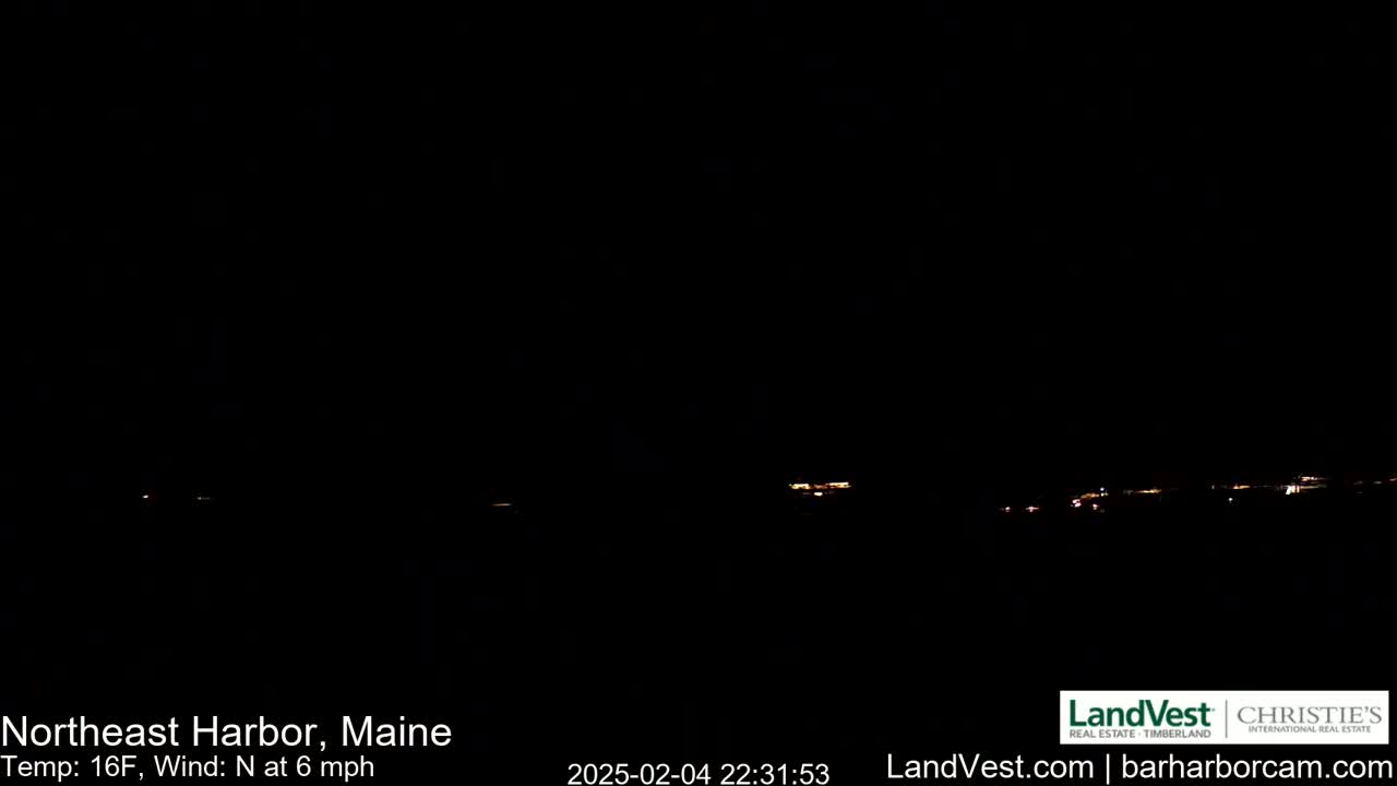 A dark nighttime scene shows a distant line of faint lights on the horizon under a clear sky, with a north wind at 6 mph and a temperature of 16°F.