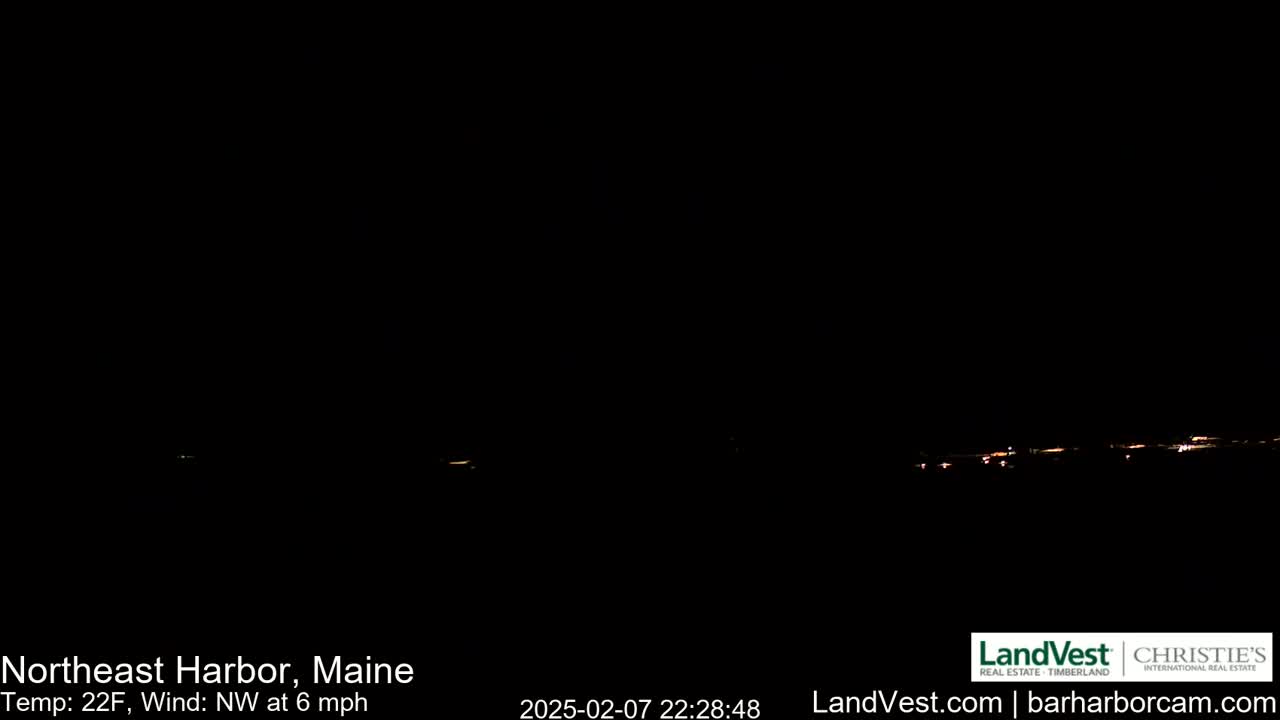 A nighttime long shot shows a dark, distant town with faint lights under a clear, dark sky.
